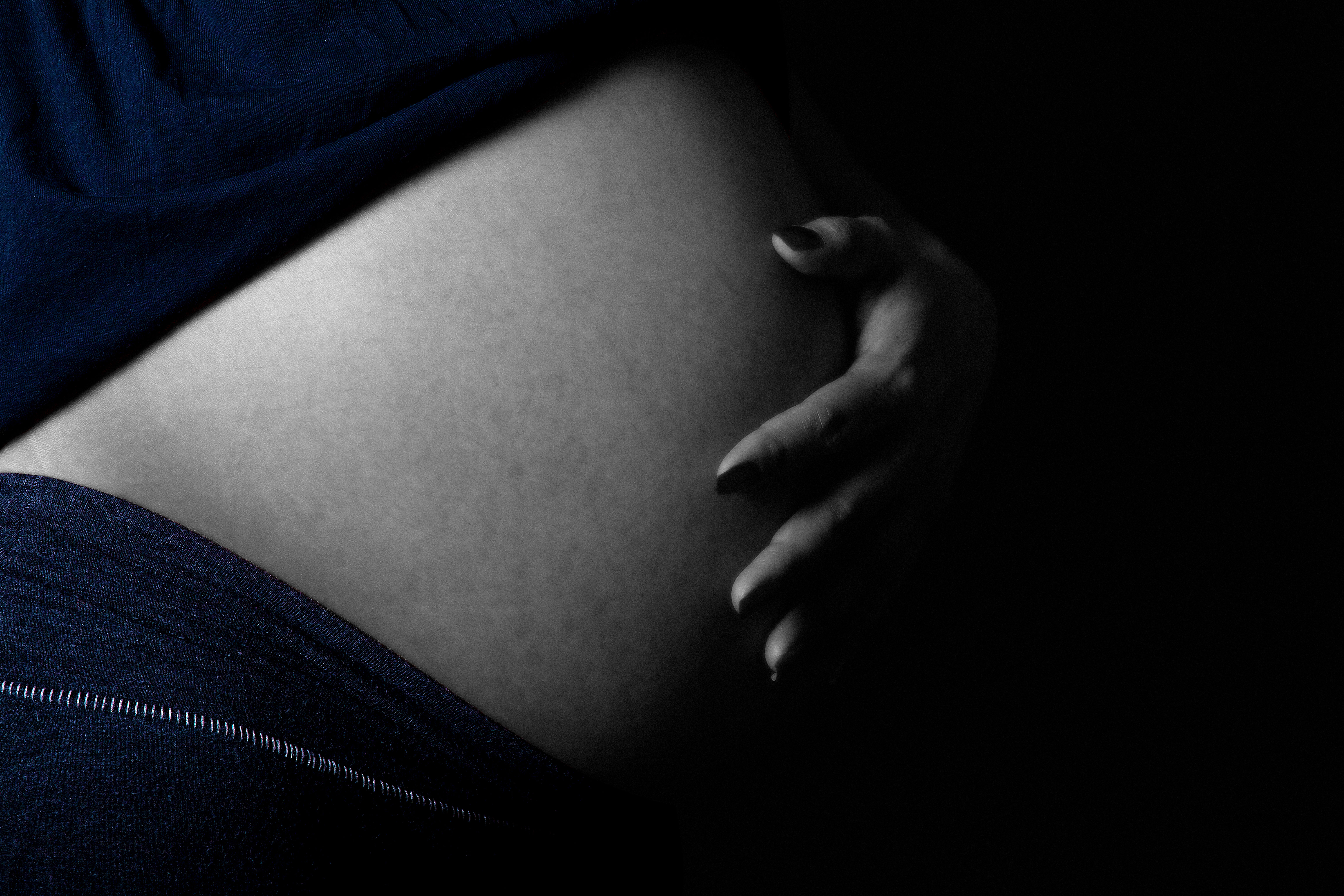 Artistic pregnancy photography close-up of pregnant belly with hand resting gently